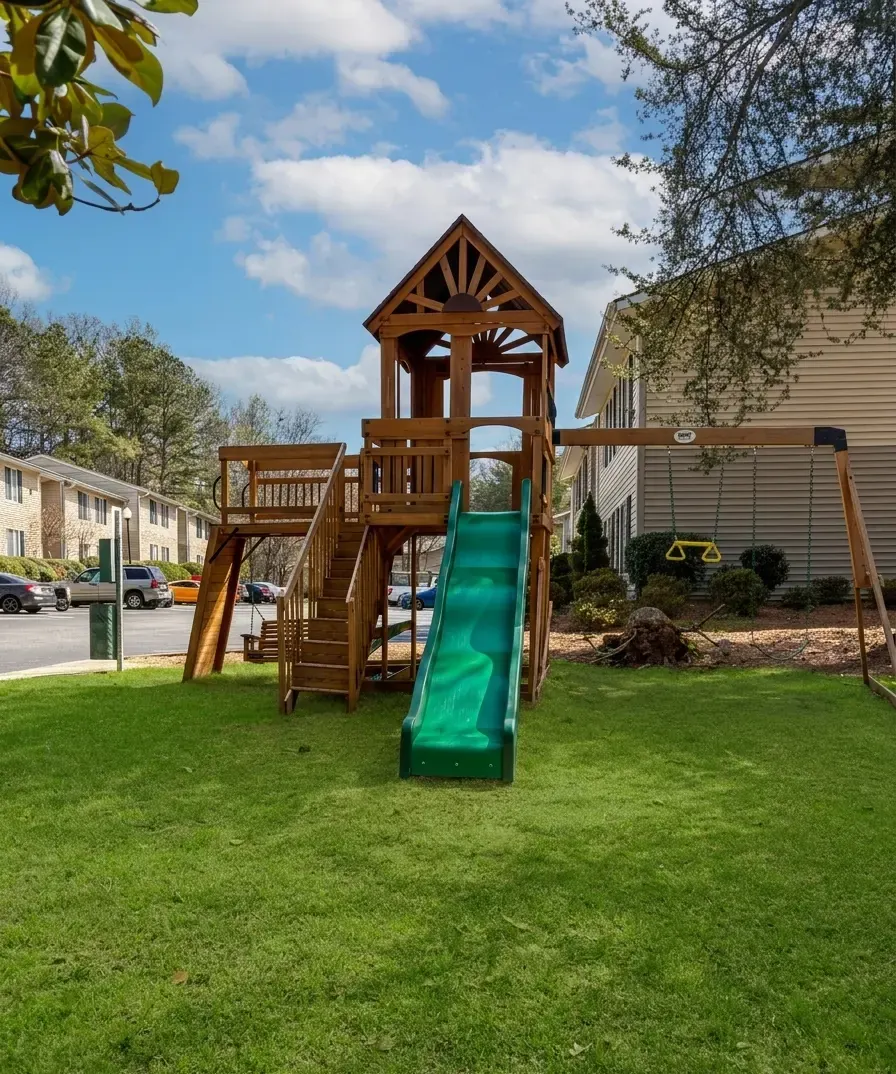 The wooden play set and green slide on the lawn at Windy Hill